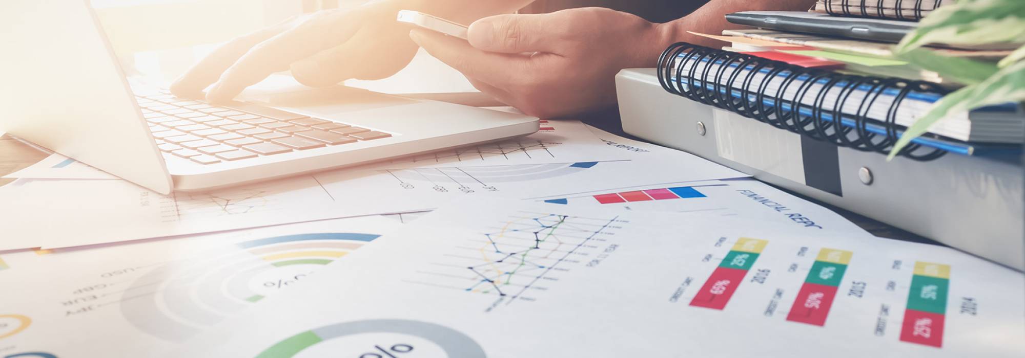 Person working at laptop surrounded by notebook and pens